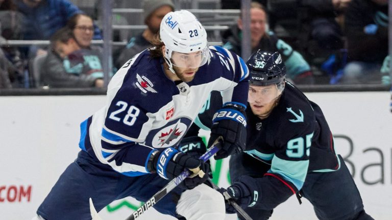 Winnipeg Jets centre Kevin Stenlund (28) and Seattle Kraken left wing Andre Burakovsky (95) vie for the puck during the third period of an NHL hockey game, Sunday, Dec. 18, 2022, in Seattle. (AP Photo/John Froschauer)