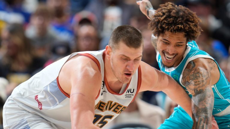 Denver Nuggets center Nikola Jokic (15) battles for control of the ball with Charlotte Hornets guard Kelly Oubre Jr., right, in the second half of an NBA basketball game Sunday, Dec. 18, 2022, in Denver. (AP Photo/David Zalubowski)