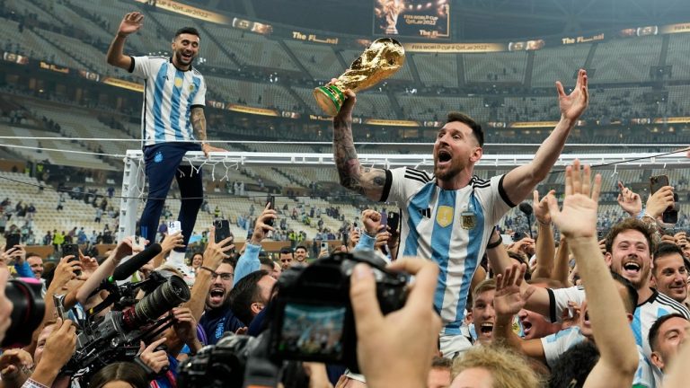 Argentina's Lionel Messi celebrates with the trophy in front of the fans after winning the World Cup final soccer match between Argentina and France at the Lusail Stadium in Lusail, Qatar, Sunday, Dec. 18, 2022. (Martin Meissner/AP)