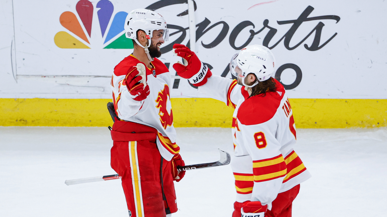 Calgary Flames defenseman Oliver Kylington, left, celebrates with defenseman Christopher Tanev, right, after scoring an empty-net against the Chicago Blackhawks during the third period of an NHL hockey game, Monday, April 18, 2022, in Chicago. (AP Photo/Kamil Krzaczynski)