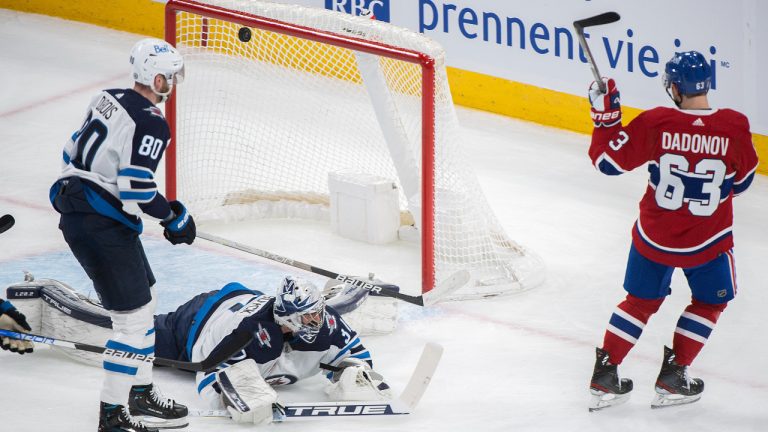 Montreal Canadiens' Evgenii Dadonov (63) scores against Winnipeg Jets goaltender Connor Hellebuyck as Jets' Pierre-Luc Dubois (80) looks on during second period NHL hockey action in Montreal, Tuesday, January 17, 2023. THE CANADIAN PRESS/Graham Hughes