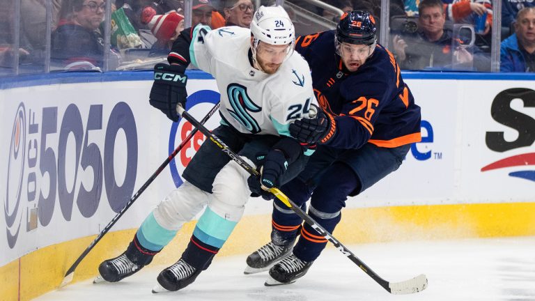 Seattle Kraken' Jamie Oleksiak (24) and Edmonton Oilers' Mattias Janmark (26) battle for the puck during second period NHL action in Edmonton on Tuesday January 17, 2023.THE CANADIAN PRESS/Jason Franson