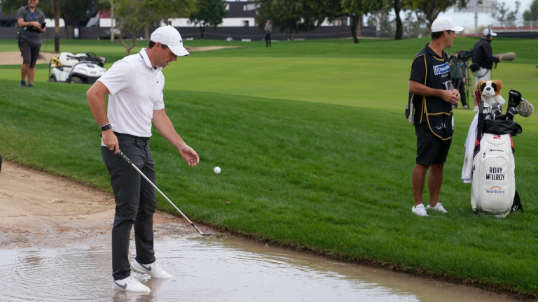 Rory McIlroy of Northern Ireland retrieves his ball from water on the 10th hole during the first round of the Dubai Desert Classic, in Dubai, United Arab Emirates, Thursday, Jan. 26, 2023. (AP)