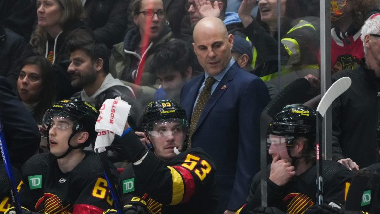 Vancouver Canucks head coach Rick Tocchet, back, stands behind Ilya Mikheyev, from left to right, Bo Horvat and Brock Boeser during the first period of an NHL hockey game against the Chicago Blackhawks in Vancouver, on Tuesday, January 24, 2023. (Darryl Dyck/CP)