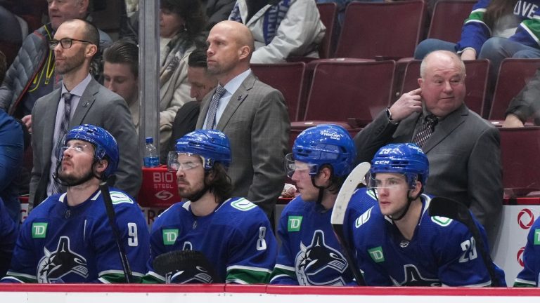 Vancouver Canucks head coach Bruce Boudreau, back right, stands on the bench with assistant coaches Jason King, back left, and Mike Yeo as J.T. Miller, from left to right, Conor Garland, Brock Boeser and Lane Pederson sit in front of them during the third period of an NHL hockey game against the New York Islanders in Vancouver, on Tuesday, January 3, 2023. (Darryl Dyck/THE CANADIAN PRESS)