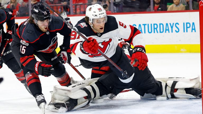 New Jersey Devils' Dawson Mercer (91) scores a goal with Carolina Hurricanes' Dylan Coghlan (15) defending during the third period of an NHL hockey game in Raleigh, N.C., Tuesday, Jan. 10, 2023. (Karl B DeBlaker/AP)