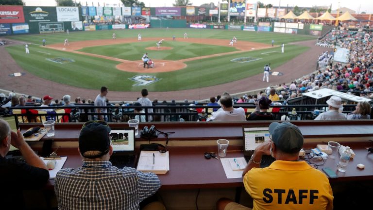 FILE - In this July 10, 2019, file photo, Ron Besaw, right, operates a laptop computer as home plate umpire Brian deBrauwere, gets signals from radar with the ball and strikes calls during the fourth inning of the Atlantic League All-Star minor league baseball game in York, Pa. The independent Atlantic League became the first American professional baseball league to let the computer call balls and strikes during the all star game. (Julio Cortez/AP File photo)