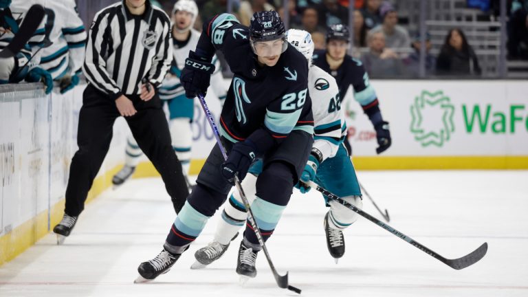 Seattle Kraken defenceman Carson Soucy slates with the puck as San Jose Sharks left wing Jonah Gadjovich (42) gives chase during the first period of an NHL hockey game. (John Froschauer/AP)