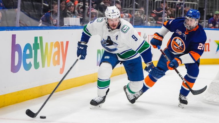 Vancouver Canucks' J.T. Miller (9) competes for control of the puck with New York Islanders' Alexander Romanov (28) during the first period of an NHL hockey game Thursday, Feb. 9, 2023, in Elmont, N.Y. (Frank Franklin II/AP)