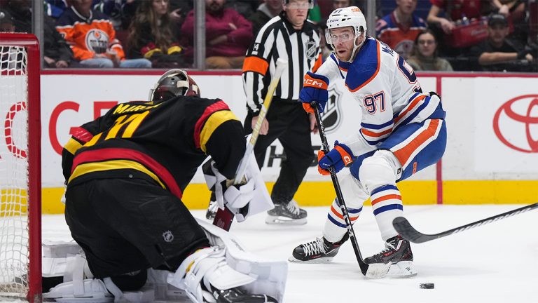 Edmonton Oilers Connor McDavid passes the puck in front of Vancouver Canucks goalie Spencer Martin during the second period of an NHL hockey game in Vancouver, on Saturday, January 21, 2023. (Darryl Dyck/CP)