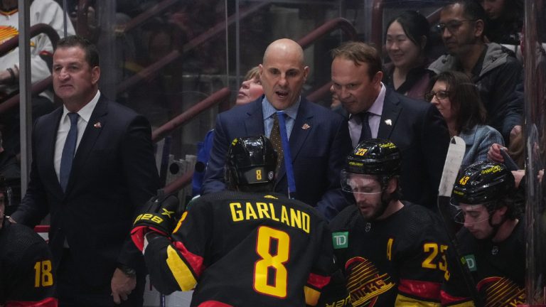 Vancouver Canucks head coach Rick Tocchet, back centre, talks to Conor Garland (8) as defensive development coach Sergei Gonchar, right, listens while assistant coach Adam Foote, back left, stands behind the bench during the first period of an NHL hockey game in Vancouver, on Tuesday, January 24, 2023. (Darryl Dyck/CP)