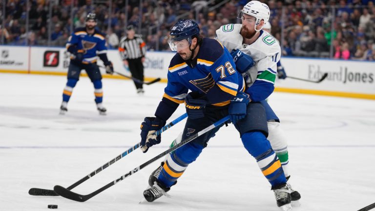 St. Louis Blues' Justin Faulk (72) and Vancouver Canucks' Filip Hronek battle for a loose puck during the second period of an NHL hockey game Tuesday, March 28, 2023, in St. Louis. (Jeff Roberson/AP)