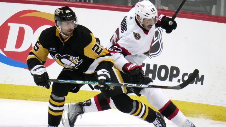 Pittsburgh Penguins' Ryan Poehling (25) and Ottawa Senators' Travis Hamonic (23) battle for puck possession during the first period of an NHL hockey game in Pittsburgh, Monday, March 20, 2023. (Gene J. Puskar/AP)