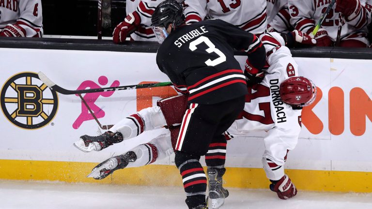 Harvard forward Casey Dornbach is checked against the boards by Northeastern defenseman Jayden Struble during the second period of the NCAA hockey Beanpot Tournament in Boston, Monday, Feb. 3, 2020. (Charles Krupa/AP)