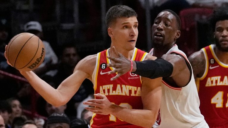 Atlanta Hawks guard Bogdan Bogdanovic (13) looks to pass the ball under pressure from Miami Heat center Bam Adebayo (13) during the second half of an NBA basketball game Saturday, March 4, 2023, in Miami. (Marta Lavandier/AP)