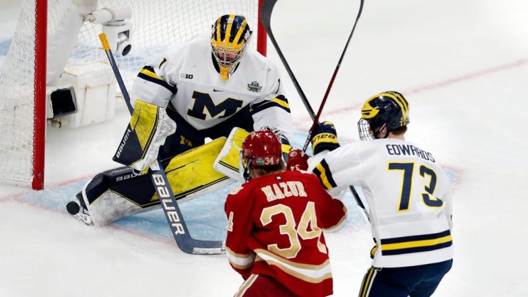 Michigan's Erik Portillo (1) blocks a shot under pressure from Denver's Carter Mazur (34) as Ethan Edwards (73) defends during the first period of an NCAA men's Frozen Four semifinal hockey game, Thursday, April 7, 2022, in Boston. (Michael Dwyer/AP Photo)