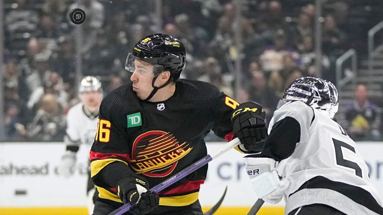 Vancouver Canucks left wing Andrei Kuzmenko, left, and Los Angeles Kings defenseman Sean Durzi watch the puck fly by during the first period of an NHL hockey game Monday, April 10, 2023, in Los Angeles. (Mark J. Terrill/AP)