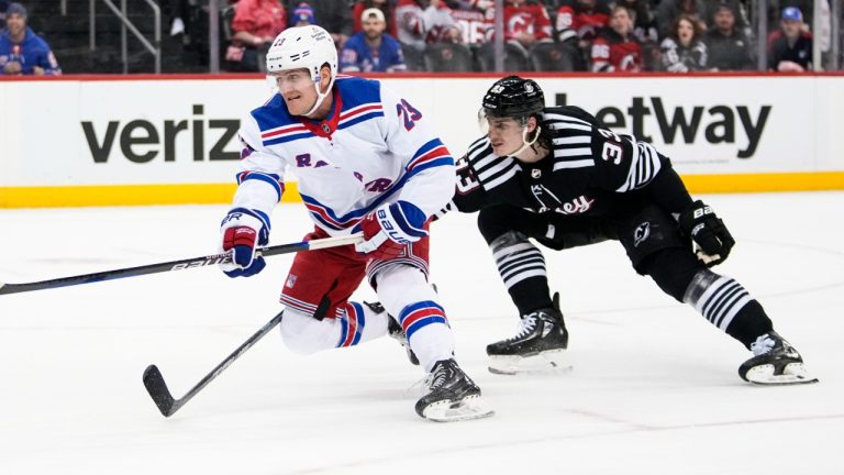 New York Rangers' Adam Fox (23) drives past New Jersey Devils' Ryan Graves (33) during the first period of an NHL hockey game Thursday, March 30, 2023, in Newark, N.J. (Frank Franklin II/AP)