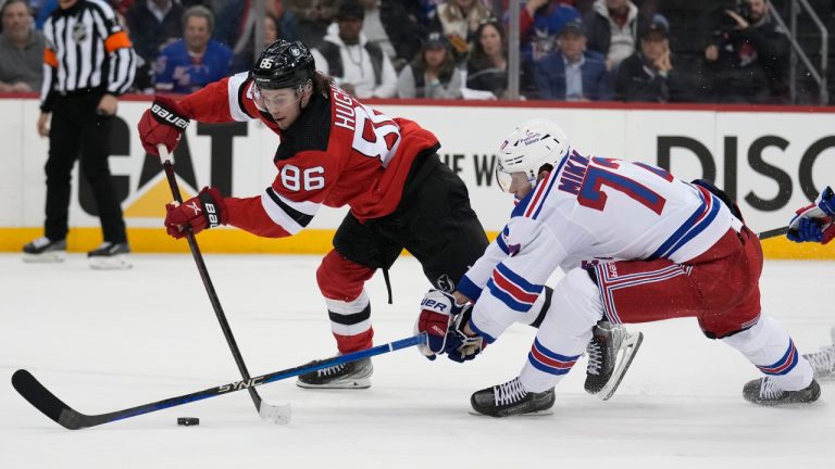 New Jersey Devils' Jack Hughes, left, shoots the puck past New York Rangers' Niko Mikkola during the second period of Game 1 of an NHL hockey Stanley Cup first-round playoff series in Newark, N.J., Tuesday, April 18, 2023. (Seth Wenig/AP)