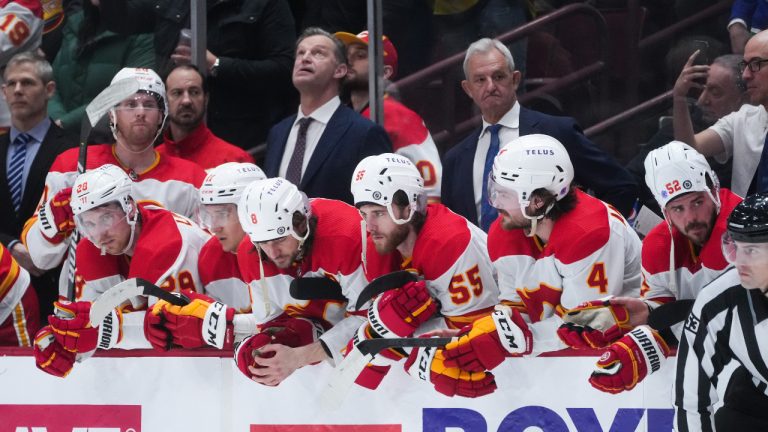 Calgary Flames' Christopher Tanev (8), Noah Hanifin (55) and MacKenzie Weegar (52) wear their helmets backwards before teammate Tyler Toffoli, not seen, took the team's final shot and failed to score during a shootout against the Vancouver Canucks during NHL hockey action in Vancouver, on Saturday, April 8, 2023. (Darryl Dyck/CP)