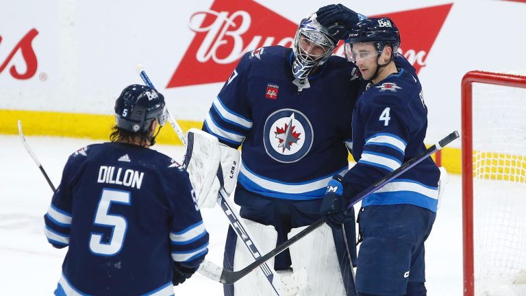 Winnipeg Jets' Brenden Dillon (5), goaltender Connor Hellebuyck (37) and Neal Pionk (4) celebrate a shutout win over the Nashville Predators at the end of third period NHL action in Winnipeg, Saturday, April 8, 2023. (CP)