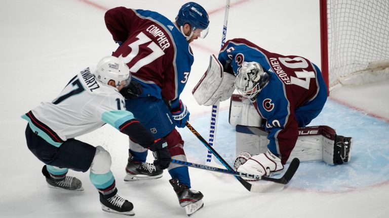 Seattle Kraken centre Jaden Schwartz, left, is blocked by Colorado Avalanche left wing J.T. Compher after putting a shot on goaltender Alexandar Georgiev during the first period of Game 5 of an NHL hockey first-round playoff series Wednesday, April 26, 2023, in Denver. (David Zalubowski/AP)