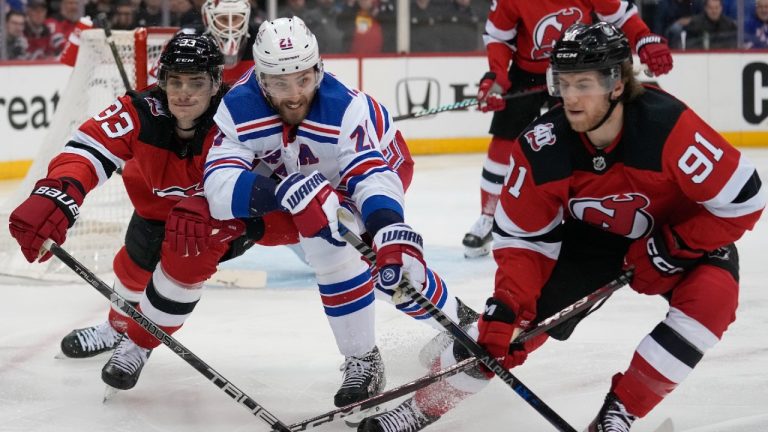 New Jersey Devils' Ryan Graves, left, and Dawson Mercer, right, and New York Rangers' Barclay Goodrow reach for the puck during the first period of Game 2 of an NHL hockey Stanley Cup first-round playoff series in Newark, N.J., Thursday, April 20, 2023. (Seth Wenig/AP)