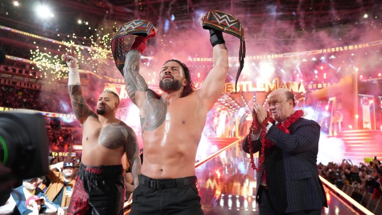 In this photo provided by WWE, Roman Reigns, centre, holds up his WWE heavyweight and universal championship belts after defeating Cody Rhodes in the main event of WrestleMania 39, Sunday, April 1, 2023, at SoFi Stadium in Inglewood, Calif. (WWE via AP)