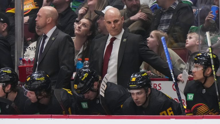 Vancouver Canucks head coach Rick Tocchet, back centre, stands behind the bench during the third period of an NHL hockey game against the Vegas Golden Knights in Vancouver, on Tuesday, March 21, 2023. (Darryl Dyck/CP)