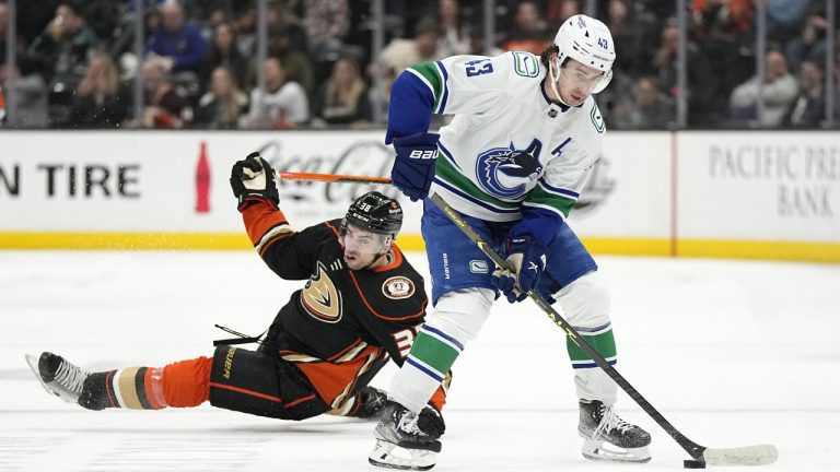 Vancouver Canucks defenceman Quinn Hughes, right, takes the puck as Anaheim Ducks center Derek Grant falls during the second period of an NHL hockey game Tuesday, April 11, 2023, in Anaheim, Calif. (Mark J. Terrill/AP)