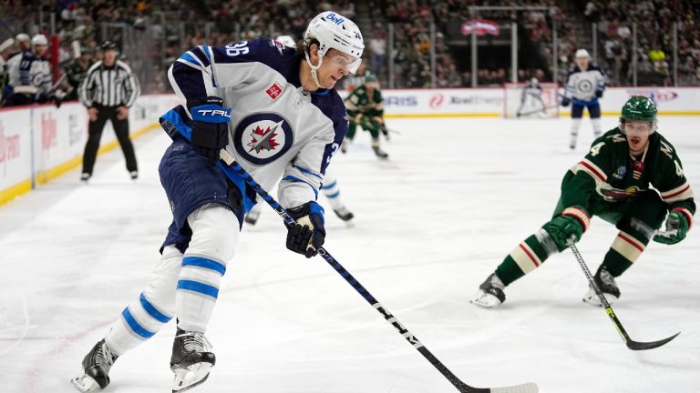 Winnipeg Jets center Morgan Barron, left, skates with the puck alongside Minnesota Wild defenseman Jon Merrill during the second period of an NHL hockey game, Tuesday, April 11, 2023, in St. Paul, Minn. (AP)