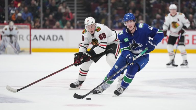 Vancouver Canucks' Cole McWard (48) skates with the puck in front of Chicago Blackhawks' MacKenzie Entwistle (58) during the first period of an NHL hockey game in Vancouver, on Thursday, April 6, 2023. (Darryl Dyck/THE CANADIAN PRESS)