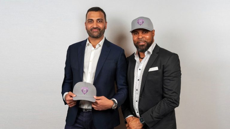 In this photo made available by Baseball United, Inc., Major League Baseball Hall of Famer and Baseball United Co-Owner, Barry Larkin, right, with Baseball United President, CEO, Chairman and Co-Owner, Kash Shaikh, holding Mumbai Cobras caps during revealing the Mumbai Cobras franchise in Cincinnati, Ohio, Friday, May 5, 2023. Baseball United, a Dubai-based organization, is swinging for the sporting history fences by establishing the first professional baseball league in the Middle East and Asia – announcing their inaugural franchise, the Mumbai Cobras, on Monday. (Baseball United, Inc. via AP)