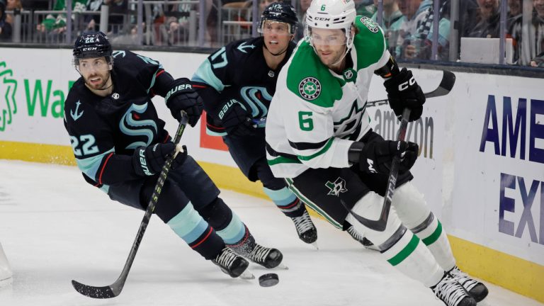 Dallas Stars defenseman Colin Miller (6) chases the puck behind the goal, followed by Seattle Kraken right wing Oliver Bjorkstrand (22) and center Jaden Schwartz (17) during the second period of an NHL hockey game Saturday, March 11, 2023, in Seattle. The Stars win 4-3 in overtime. (AP Photo/John Froschauer) 