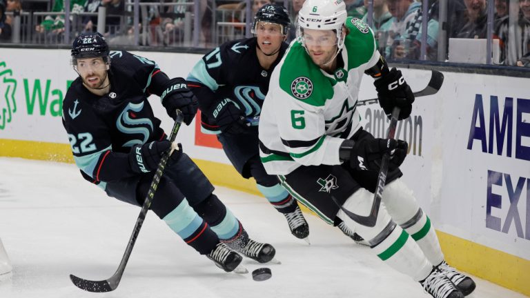 Dallas Stars defenseman Colin Miller (6) chases the puck behind the goal, followed by Seattle Kraken right wing Oliver Bjorkstrand (22) and center Jaden Schwartz (17) during the second period of an NHL hockey game Saturday, March 11, 2023, in Seattle. The Stars win 4-3 in overtime. (AP Photo/John Froschauer) 