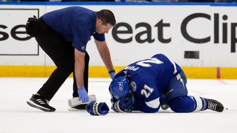 A trainer checks on Tampa Bay Lightning centre Brayden Point (21) after he was shaken up on a check by the Toronto Maple Leafs during the third period in Game 3 of an NHL hockey Stanley Cup first-round playoff series Saturday, April 22, 2023, in Tampa, Fla. (Chris O'Meara/AP) 