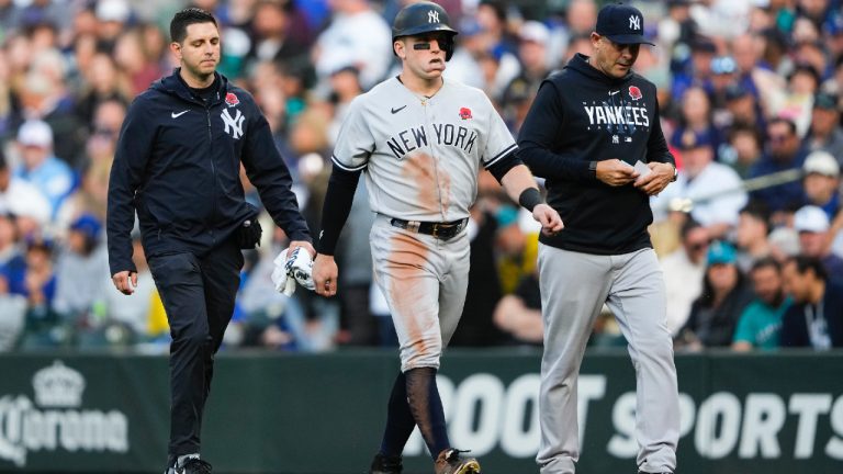 New York Yankees' Harrison Bader, centre, leaves a baseball game with an apparent injury while accompanied by a trainer, left, and manager Aaron Boone, right, during the third inning of a baseball game against the Seattle Mariners, Monday, May 29, 2023, in Seattle. (Lindsey Wasson/AP)