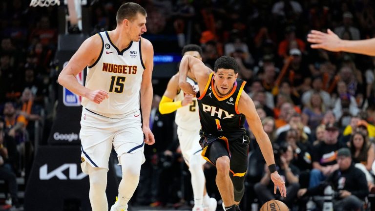 Phoenix Suns guard Devin Booker drives as Denver Nuggets center Nikola Jokic looks on during the first half of Game 4 of an NBA basketball Western Conference semifinal game, Sunday, May 7, 2023, in Phoenix. (Matt York/AP Photo)