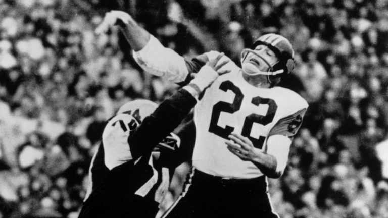 Joe Kapp (22) quarterback for the B.C. Lions manages to get his pass away before Pete Neumann (74) of the Hamilton Tiger Cats tackles him in the third quarter of CFL Grey Cup action in Toronto on Nov. 28, 1964. Kapp, the former CFL and NFL star quarterback, has died. He was 85. According to CFL officials, Kapp died Monday night. (CP)