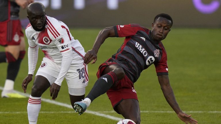 Former Toronto FC midfielder Richie Laryea (22) goes to ground to control the ball as New England Revolution midfielder Ema Boateng (18) defends during first half MLS soccer action in Toronto on Saturday May 6, 2023. (Frank Gunn/CP)