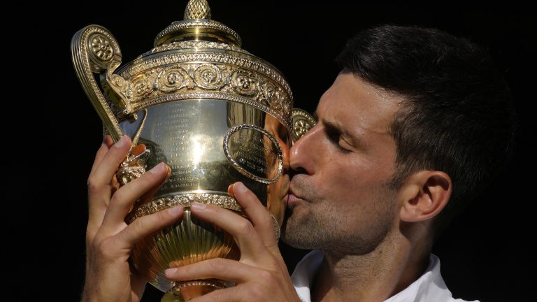 Serbia's Novak Djokovic kisses the trophy as he celebrates after beating Australia's Nick Kyrgios to win the final of the men's singles on day fourteen of the Wimbledon tennis championships in London, Sunday, July 10, 2022. (AP Photo/Kirsty Wigglesworth)