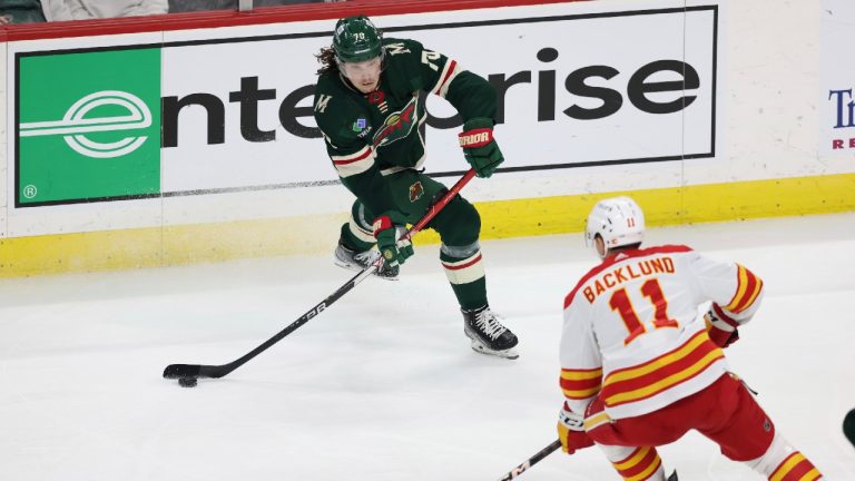 Oskar Sundqvist (70) passes the puck against Calgary Flames centre Mikael Backlund (11) during the third period of an NHL hockey game Tuesday, March 7, 2023, in St. Paul, Minn. (Stacy Bengs/AP)