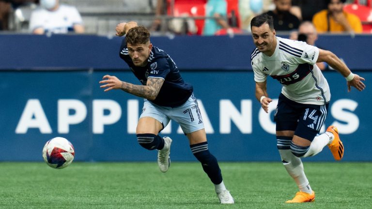 Sporting Kansas City's Marinos Tzionis (77) and Vancouver Whitecaps' Luís Martins (14) chase the ball during the first half of an MLS soccer match in Vancouver, on Saturday, June 3, 2023. Ethan Cairns/THE CANADIAN PRESS