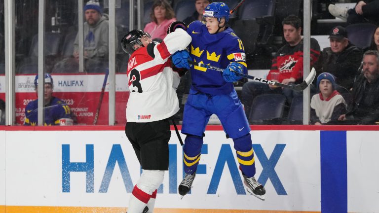 Sweden's Fabian Wagner, right, leaps to avoid a hit by Austria's Lukas Horl during third period IIHF World Junior Hockey Championship hockey action in Halifax on Monday, December 26, 2022. (Darren Calabrese/CP)