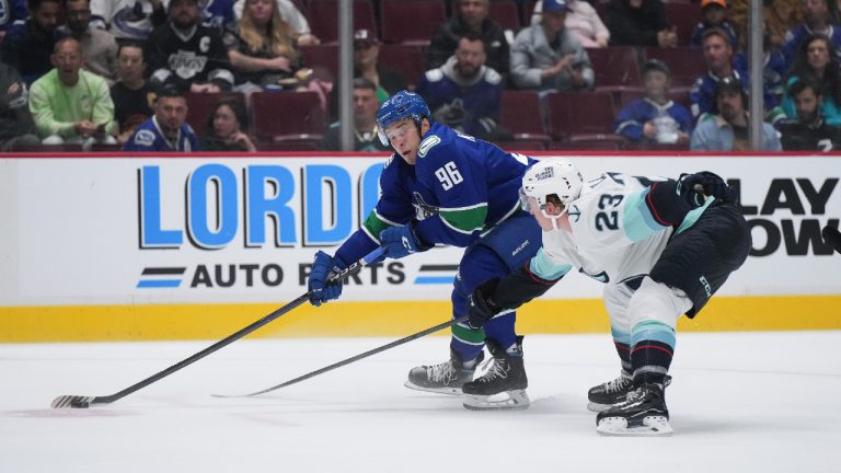 Vancouver Canucks' Andrei Kuzmenko (96), of Russia, passes the puck while being checked by Seattle Kraken's Gustav Olofsson (23), of Sweden, during the first period of a pre-season NHL hockey game in Vancouver, on Thursday, September 29, 2022. (Darryl Dyck/CP)