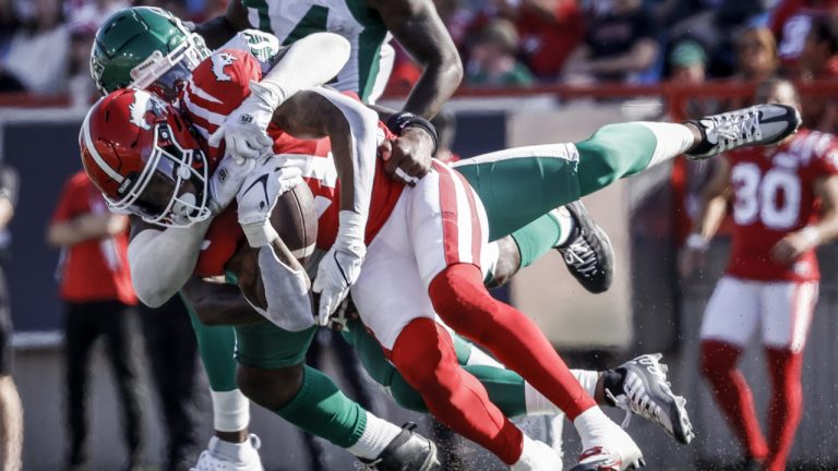 Saskatchewan Roughriders linebacker Larry Dean, centre, brings down Calgary Stampeders receiver Malik Henry during first half CFL football action in Calgary, Alta., Saturday, June 24, 2023. (Jeff McIntosh/CP)