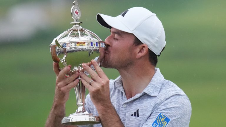 Nick Taylor, of Canada, kisses the trophy after winning the Canadian Open championship on the fourth playoff hole against Tommy Fleetwood, of Southport, U.K., in Toronto on Sunday, June 11, 2023. (CP)