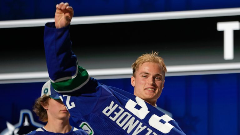 Tom Willander puts on a Vancouver Canucks jersey after being picked by the team during the first round of the NHL hockey draft Wednesday, June 28, 2023, in Nashville, Tenn. (George Walker IV/AP)