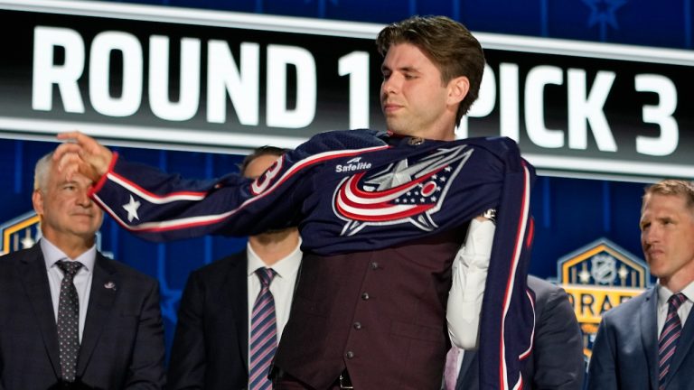 Adam Fantilli puts on a Columbus Blue Jackets jersey after being picked by the team during the first round of the NHL hockey draft Wednesday, June 28, 2023, in Nashville, Tenn. (George Walker IV/AP Photo)