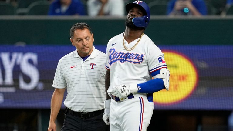 Texas Rangers head athletic trainer Matt Lucero, left, attends to Adolis Garcia, right, after Garcia was hit by a pitch in the eighth inning of a baseball game against the Tampa Bay Rays, Wednesday, July 19, 2023, in Arlington, Texas. Garcia left the game with an unknown left arm injury. (Tony Gutierrez/AP)